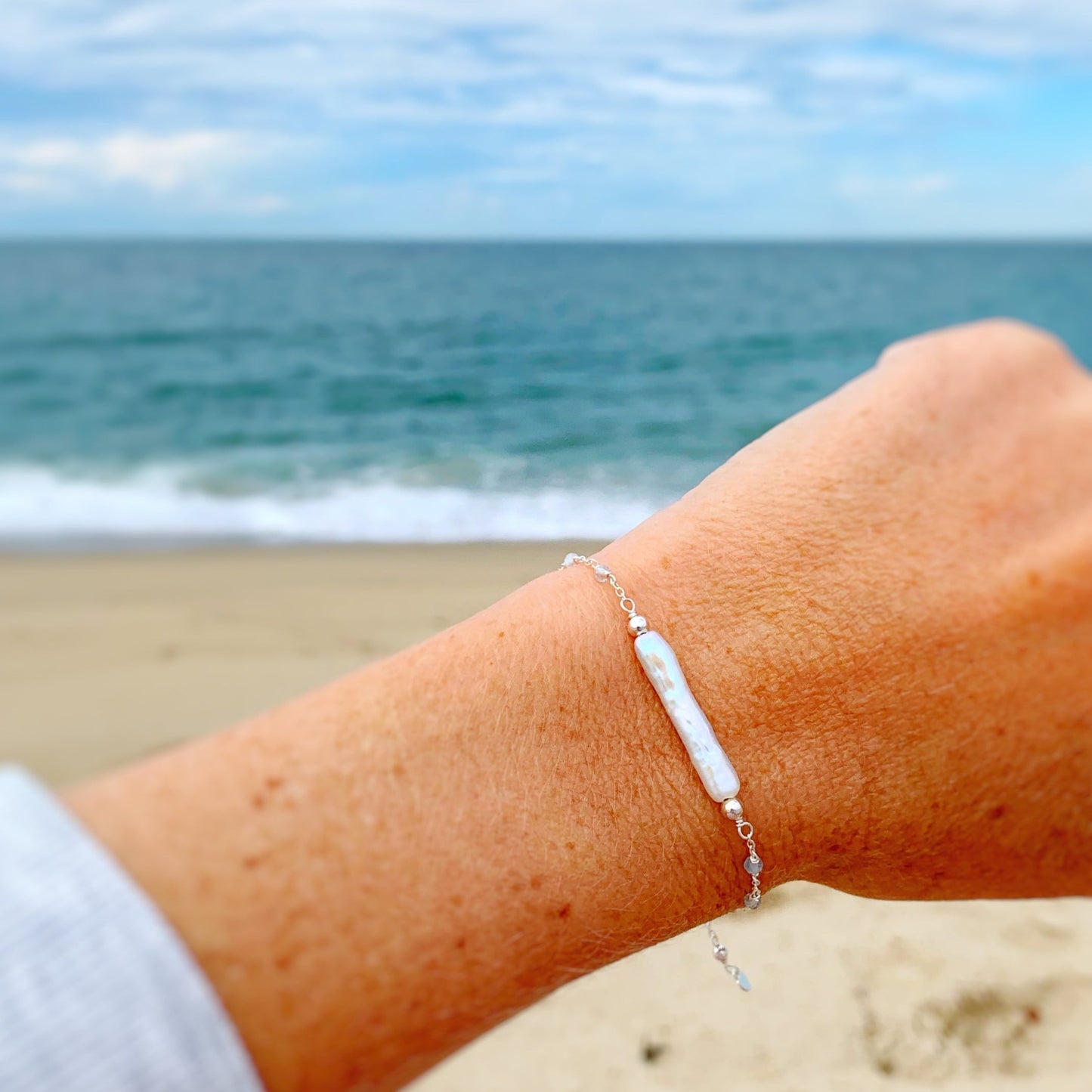 Image of the Truro bracelet in sterling silver photographed close up on a wrist with a soft blurry beach background