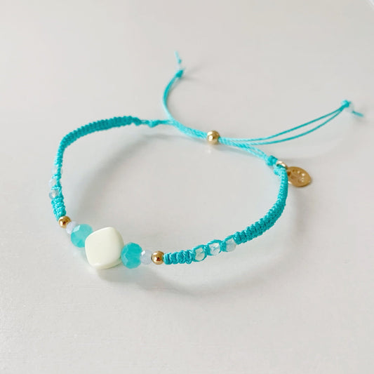 The captiva macrame bracelet in color blue crush pictured on top of a white surface