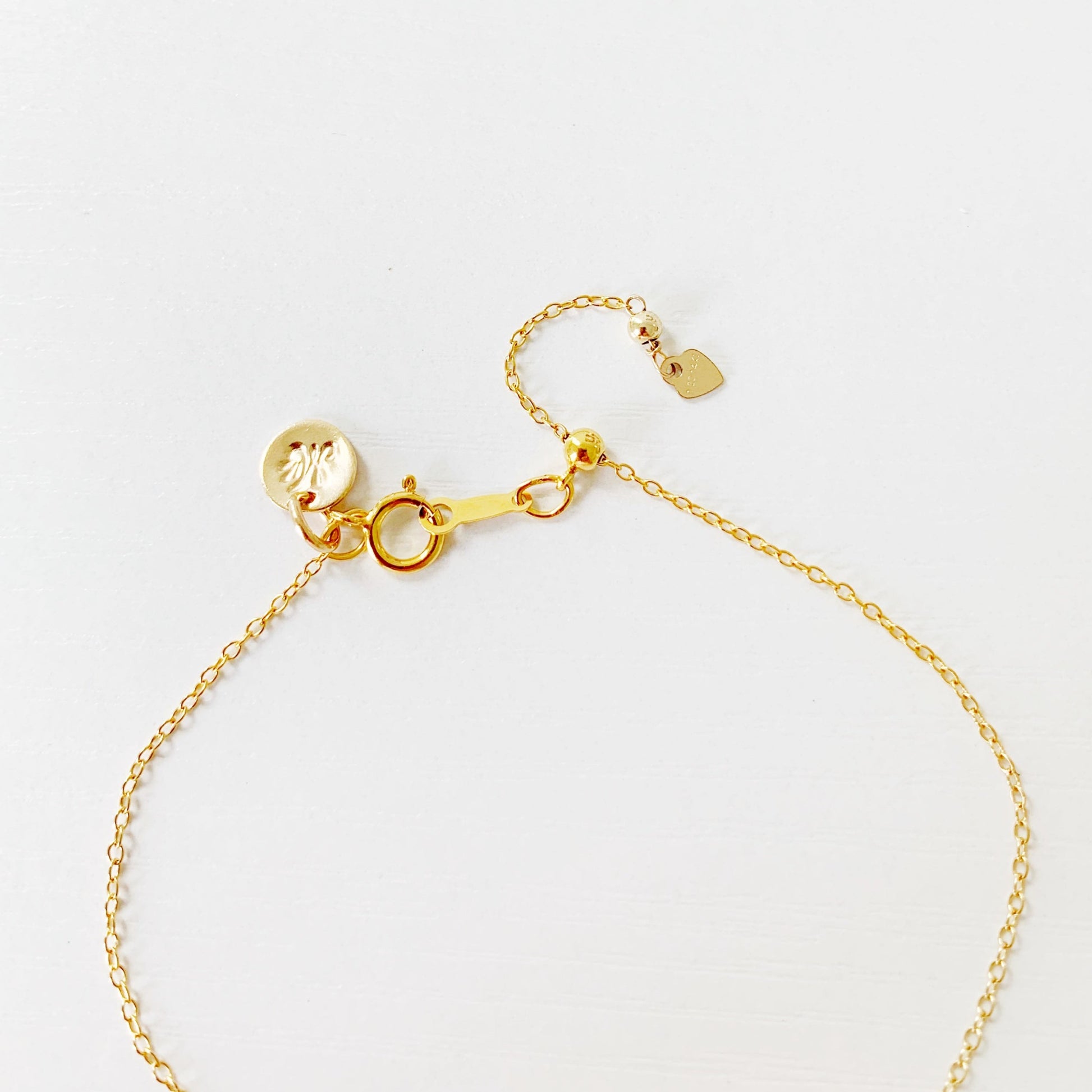 this image is of the back half of the laguna bracelet showing the 14k gold filled cable chain and slide bead near the clasp. this is photographed on a white surface