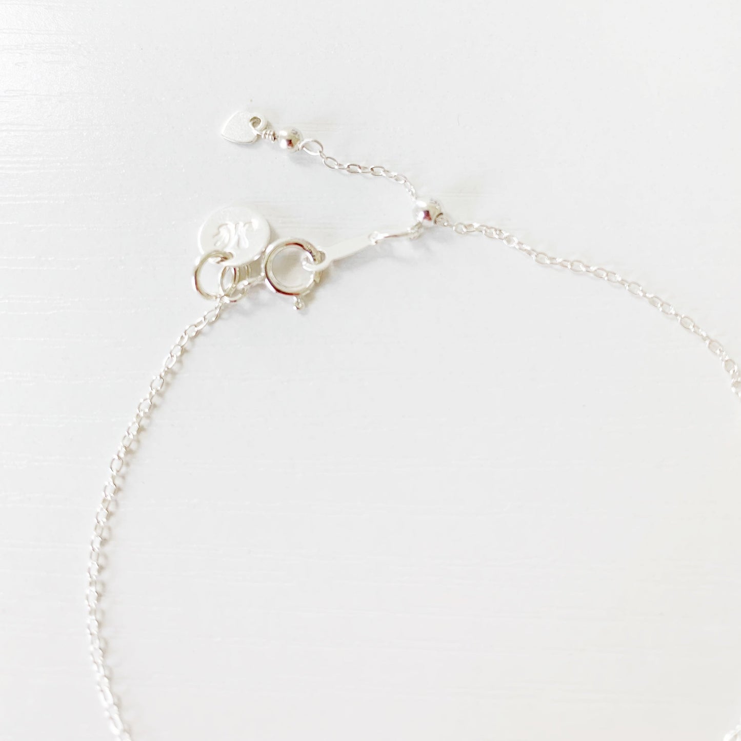 this is an image of the back of the laguna bracelet showing the sterling silver cable chain and slide bead near the clasp making the bracelet adjustable. this is photographed on a white surface