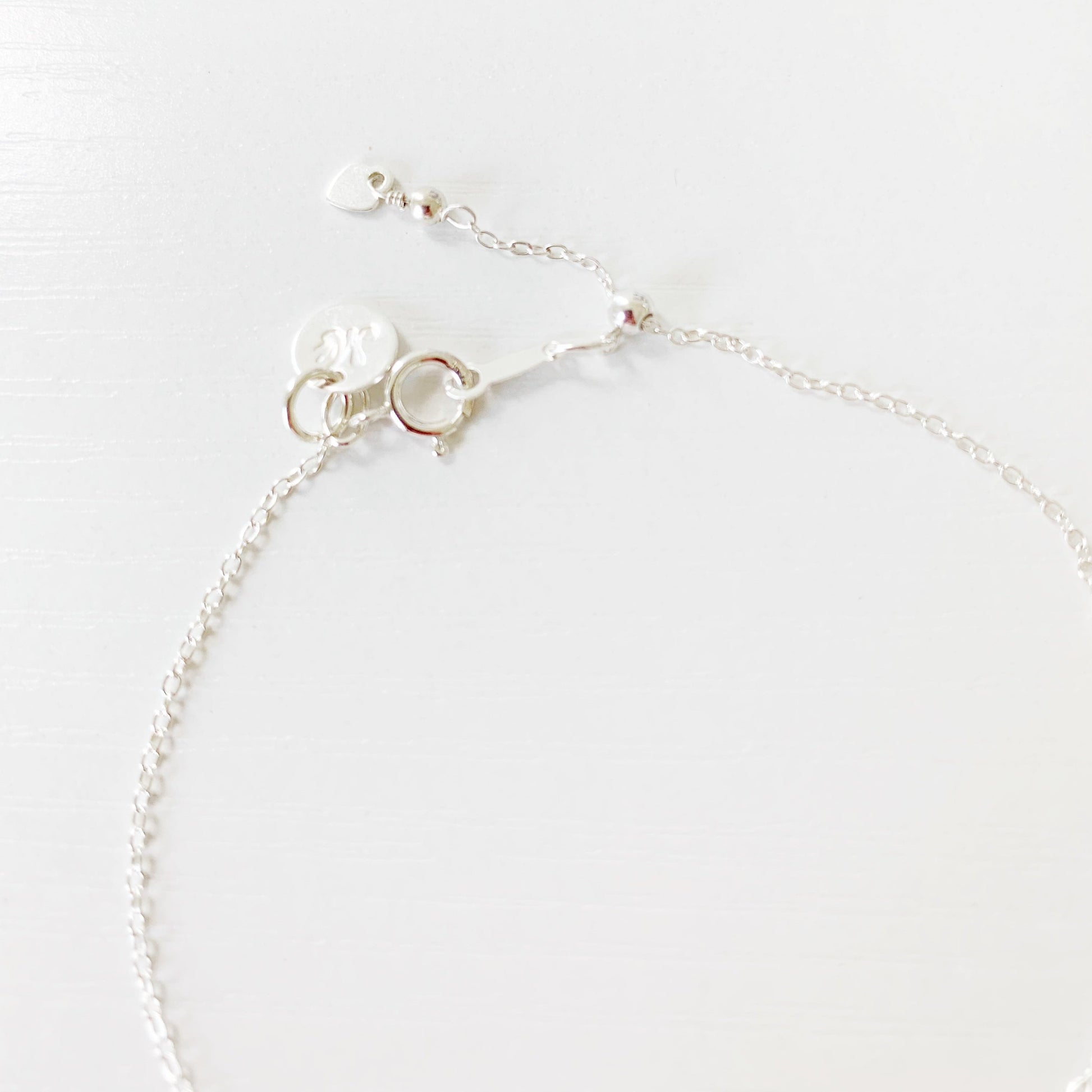 this is an image of the back of the laguna bracelet showing the sterling silver cable chain and slide bead near the clasp making the bracelet adjustable. this is photographed on a white surface