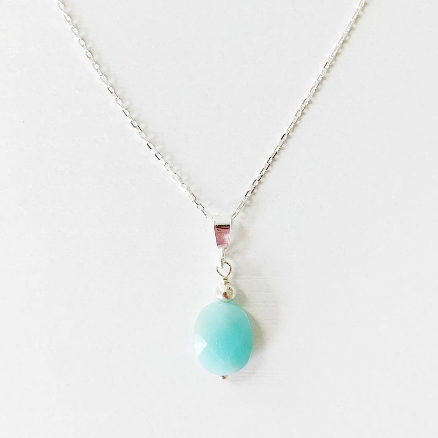 the mermaids and madeleines laguna necklace is designed with a faceted amazonite bead suspended as a pendent from sterling silver chain and findings. this necklace is photographed on a white surface