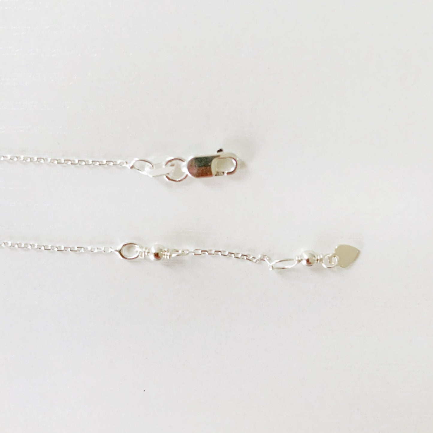 this image shows the closure of the pink azalea necklace. just the sterling silver clasp and the chain extender are in view and photographed on a white surface