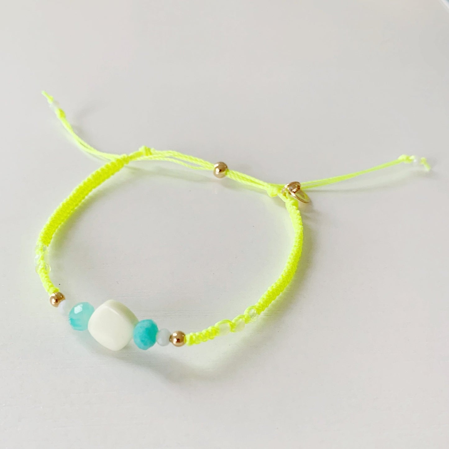 a top view of the neon yellow captiva macrame bracelet in a mermaids and madeleines on a white surface