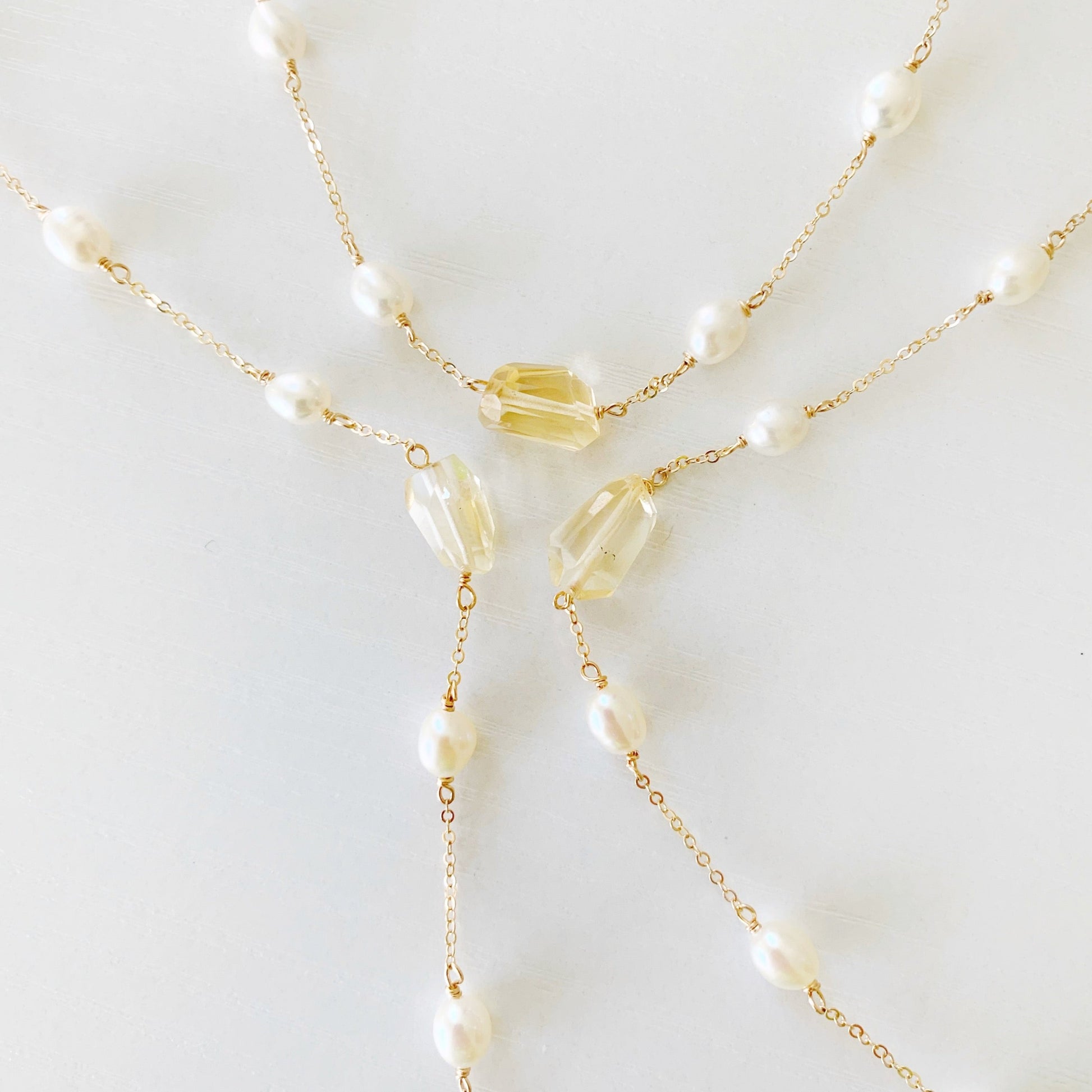 A photo of 3 sun and snow mermaids and madeleines necklaces. the necklaces are swirled in a flatlay on a white surface