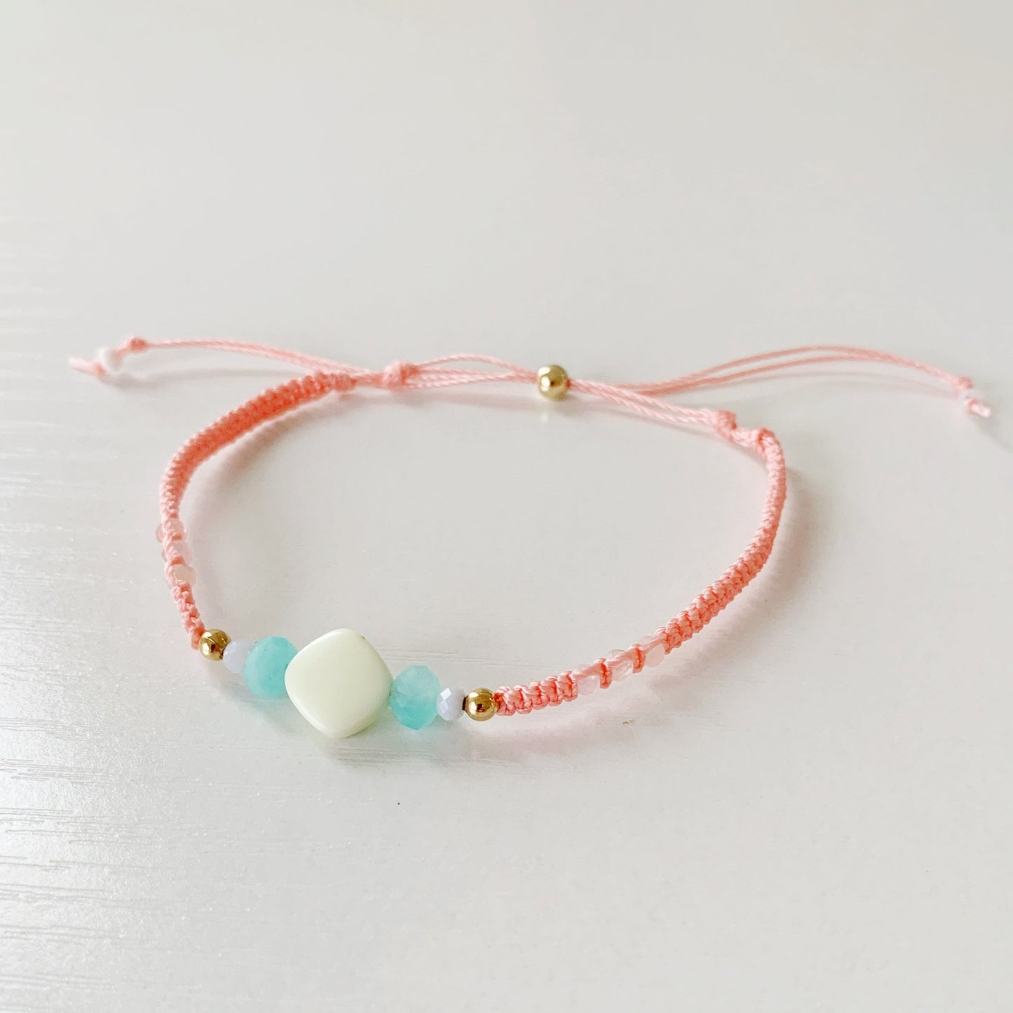 peach macrame friendship bracelet pictured  on a white background