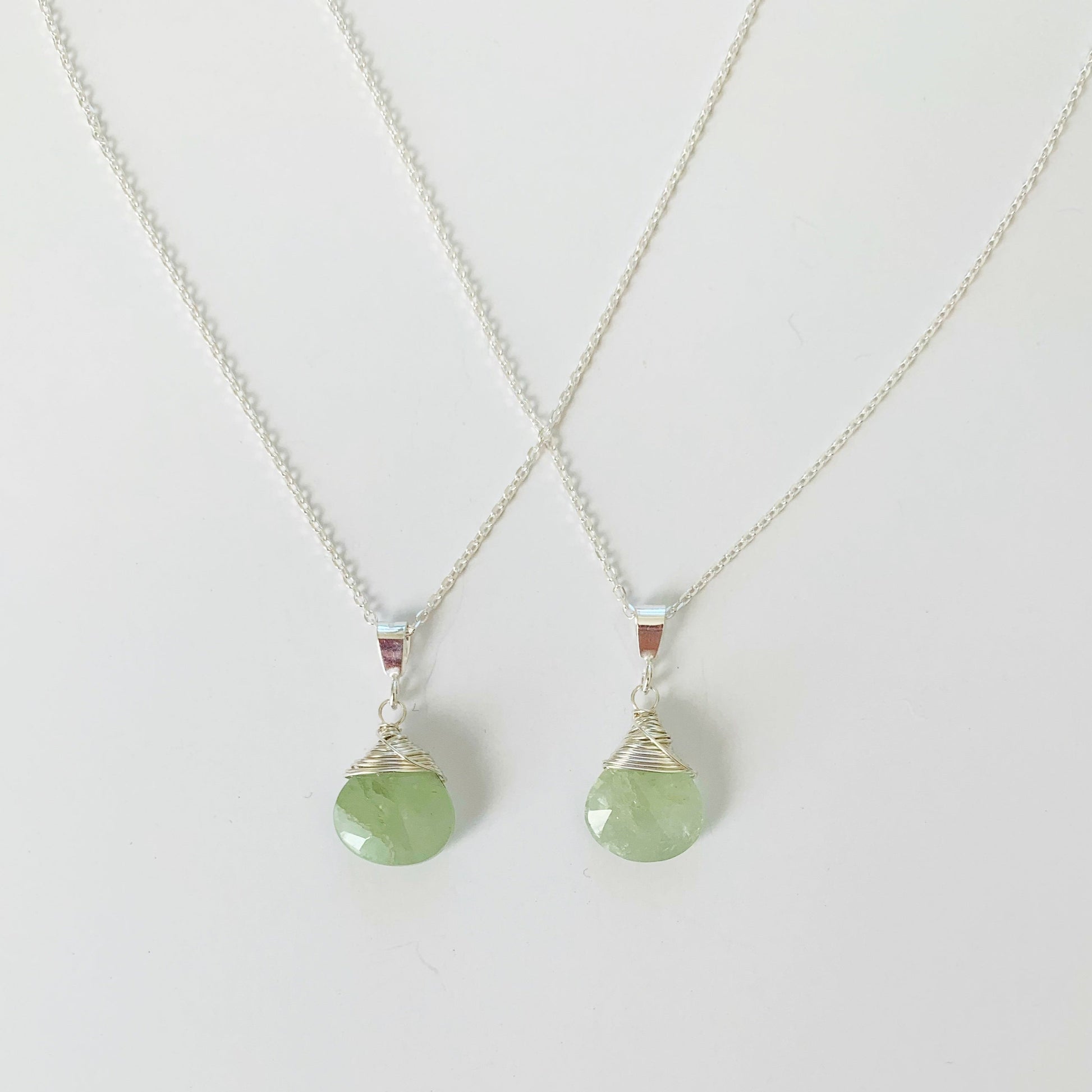 2 raindrop wire wrapped necklaces in sterling silver and aquamarine pictured on a white surface