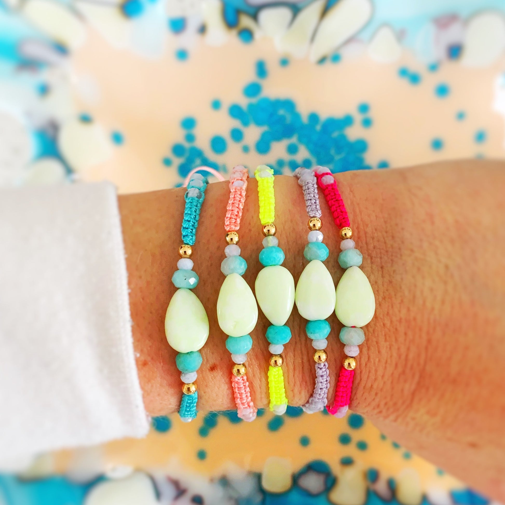 Captiva Macramé bracelets in all colorways, bright aqua blue, peach, neon yelllow, lavender and hot pink with teardrop lime jade stone at center. All bracelets worn stacked on a wrist