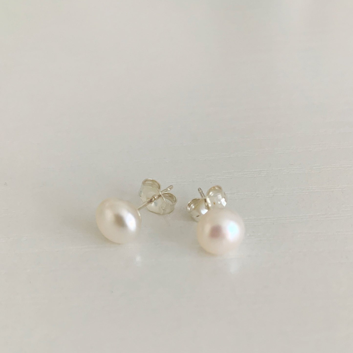 Pearlfect Day pearl post earrings by mermaids and madeleines feature freshwater button pearls and sterling silver post earrings. this pair is photographed on a white surface